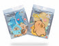 Two packages of kakaziyan Restoring Eye Masks held in a hand against a background of green foliage. One package contains a blue mask and the other contains a yellow mask, both featuring cute cartoon capybara illustrations.